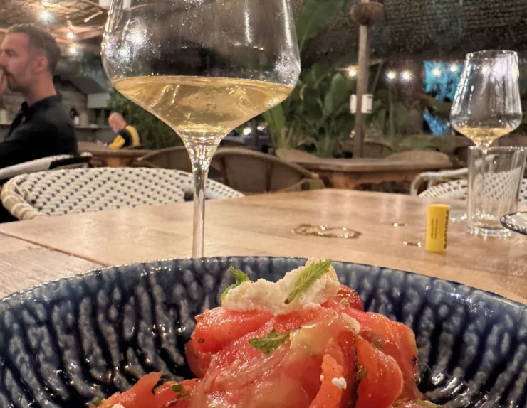 Plato de tomates frescos y copa de vino blanco en un bar de vinos de Sitges al anochecer