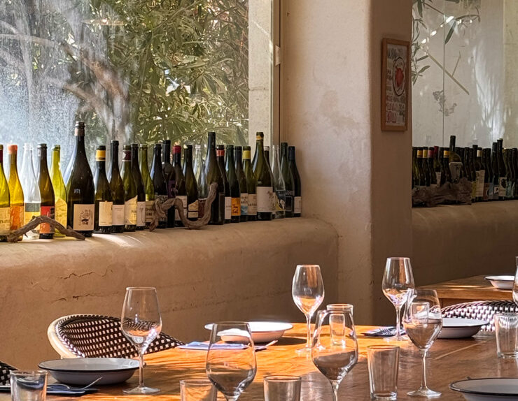 Sala de un restaurante de Sitges, mesa puesta ante una pared de botellas de vino