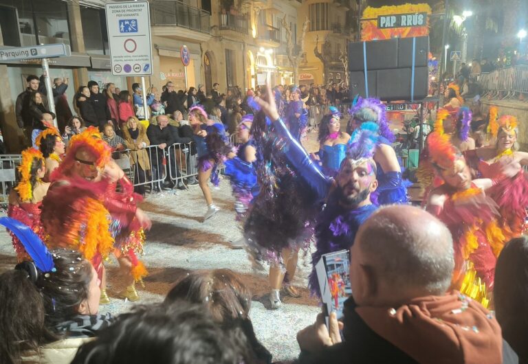 Desfile nocturno del carnaval de Sitges, bailarines con plumas y purpurina en la Rua de l'Extermini