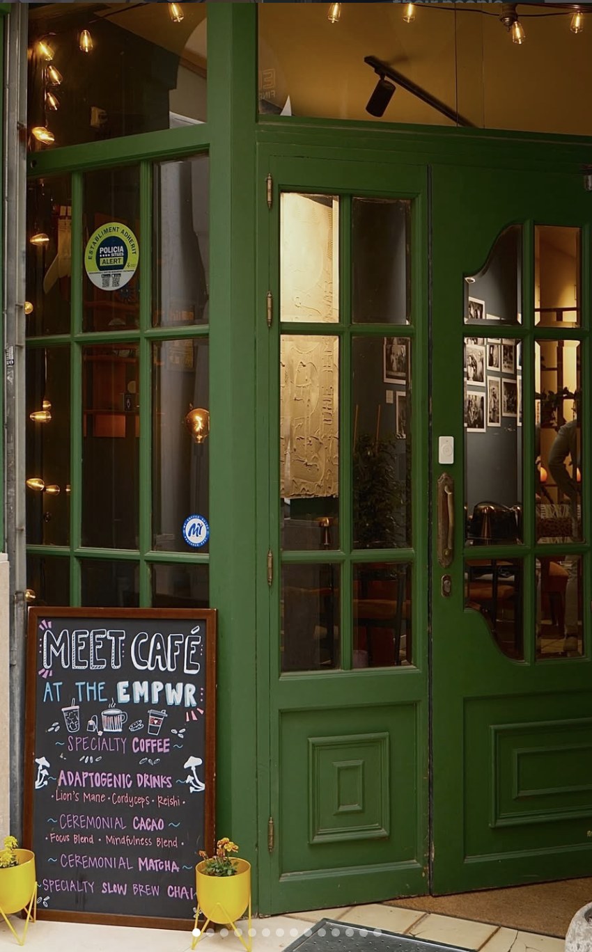 La entrada verde y el menú en pizarra de The EMPWR, cafetería de café de especialidad y coworking en Sitges