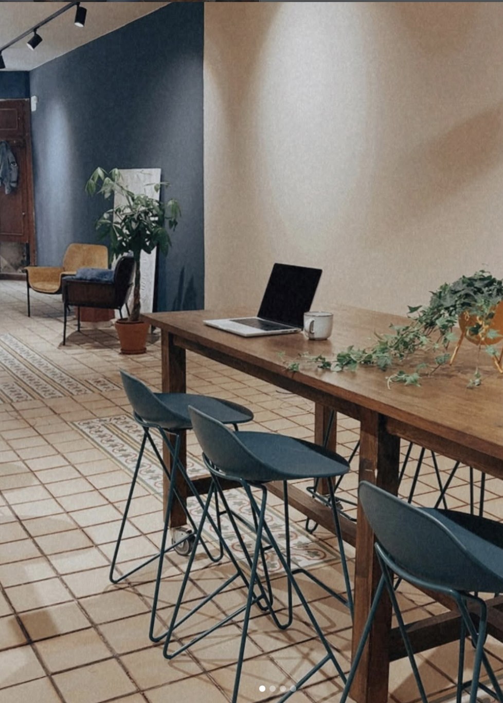 Mesa de trabajo comunitaria con un portátil en la cafetería de coworking The EMPWR en Sitges