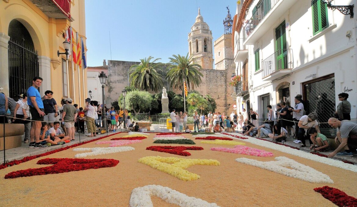 Alfombra de flores de colores en una plaza del centro histórico de Sitges frente al campanario