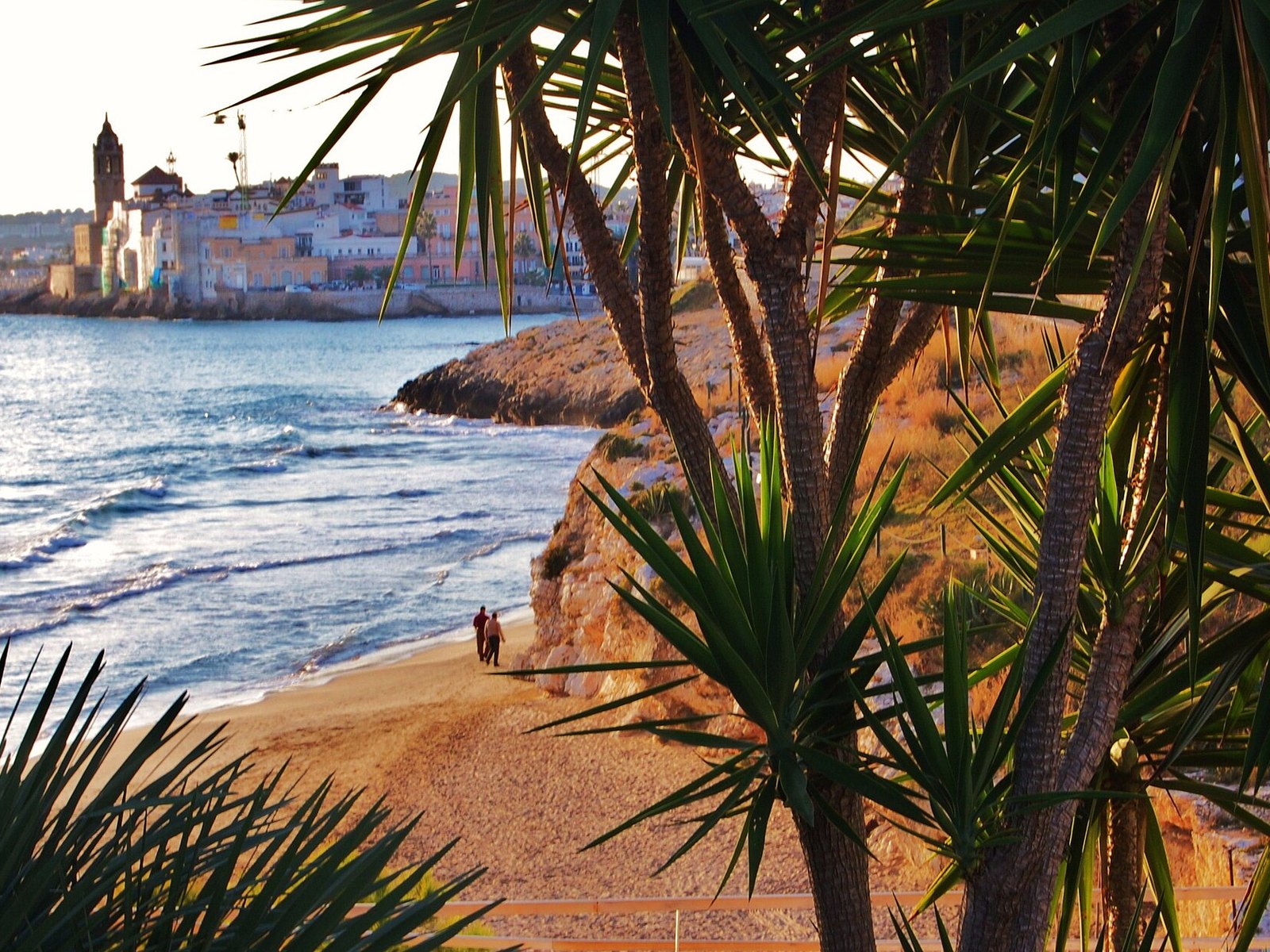 Cala Balmins en Sitges, una cala de arena entre las rocas con la iglesia al fondo